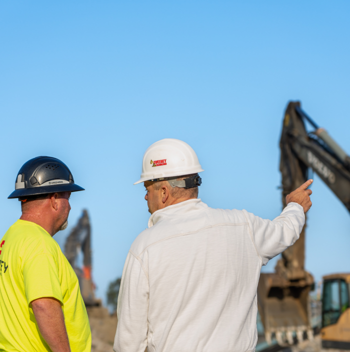 Sweeney, employees, pointing at excavator, black hard hat, white hard hat, 24075_BUILDWITT_0287-1